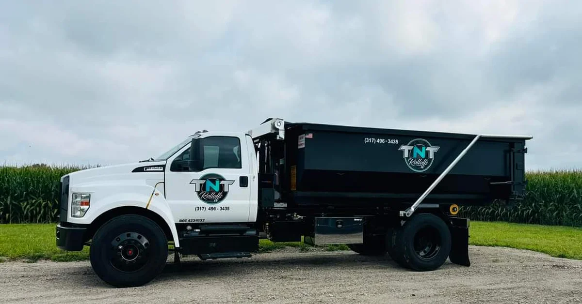 TNT Rolloffs white dump truck with black dumpster bed in rural Indiana